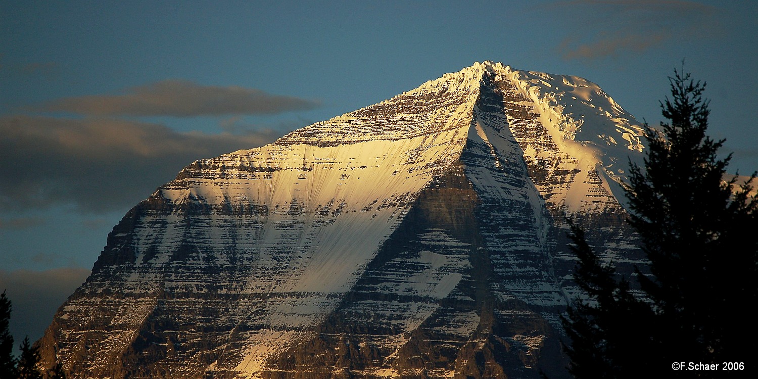 Horizonte 172.jpg - Mt. Robson in warm evening light, seenfrom the parking lot along Hwy 5  Mt. Robson is thehighest mountain in the Canadian Rockies with 3954mor 13006ft, first ascented July 1913.   click here for Google Maps View   Position (peak):   N53°06'39"/W119°09'24" Position (camera): N52°59'40" W119°18'16" Camera: Nikon D50, 200mm lens, date: 27/09/2006, 18:24 local